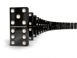 A row of black dominoes with white dots stands upright, each placed closely behind the other. This visually striking perspective epitomizes the Domino Stress Effect, hinting at chain reactions. The focus is on the foreground piece, captivatingly illustrating one of the quickest ways to beat stress.