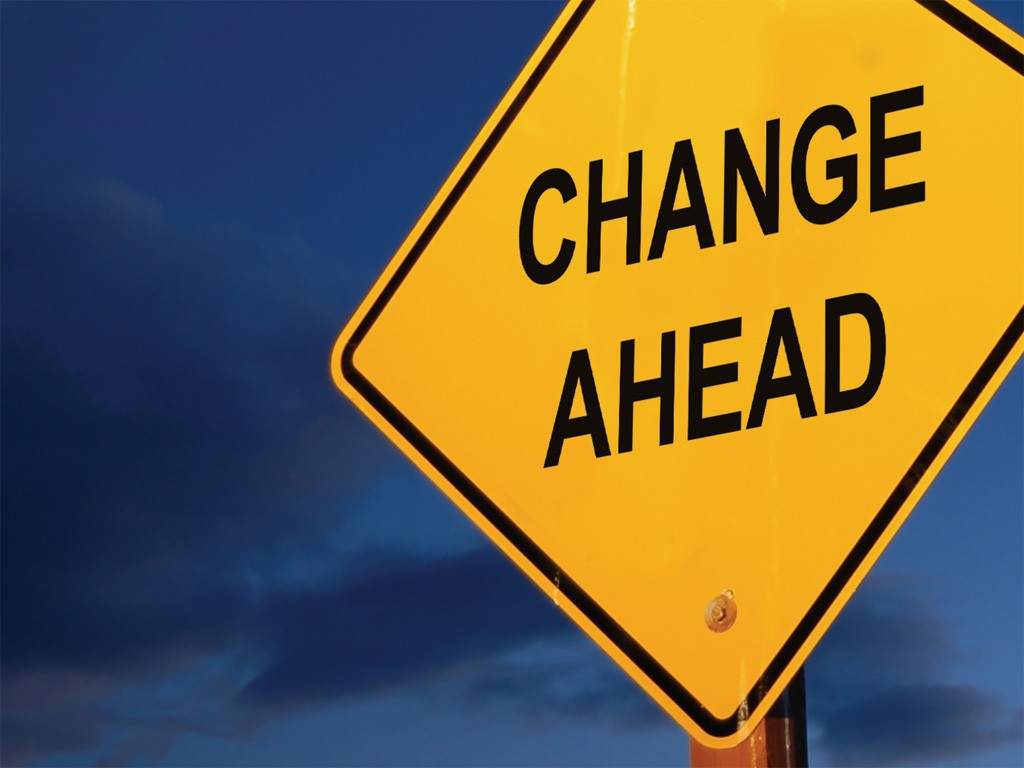 A yellow diamond-shaped road sign with the words "CHANGE AHEAD" looms against a backdrop of a dark, cloudy sky, reminding us that even stressful change can be navigated with clarity and calm through practices like Neurosculpting meditation.
