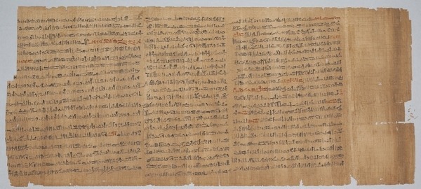 Ancient papyrus scroll featuring dense black hieroglyphic script arranged in vertical columns. The text is worn and shows signs of age, with minor tears and frayed edges on the papyrus surface, reminiscent of Susan Aplin Pogue's fascination with history, where even blank pages tell a story.