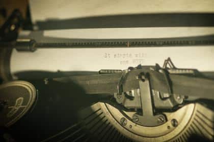 A close-up of a vintage typewriter with a sheet of paper bearing the partially typed text "it starts with one word" evokes the essence of Vija Rogozina's latest book. The keys and paper are in focus under warm lighting, inviting reflection on how we often fall into an authenticity trap.