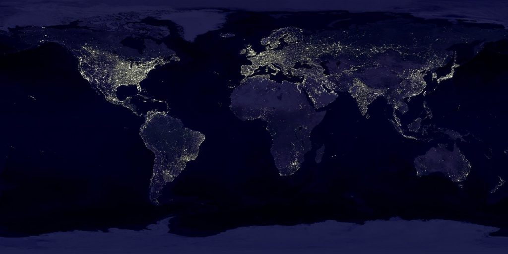 A world map at night reveals city lights illuminating continents, highlighting the dense populations of North America, Europe, and parts of Asia. Mapping urban life from space, other regions like Africa and parts of South America show fewer lights.