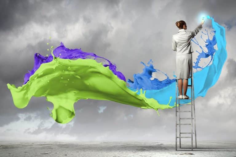 A person in a gray suit stands on a ladder under a cloudy sky, painting vibrant, swirling splashes of green, blue, and purple across the sky.