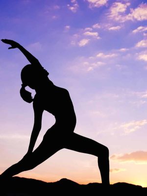 A silhouette of a person engaging in yoga graces the vibrant sunset sky, with colorful clouds casting their hues over distant hills, embodying the art of neurosculpting in perfect harmony.