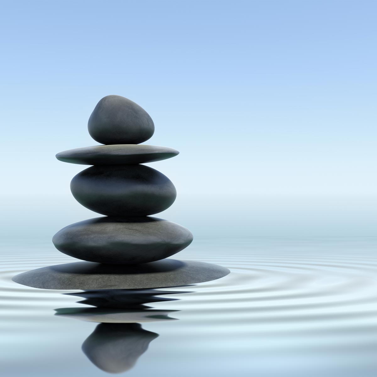 A stack of smooth stones balances on a tranquil water surface, creating gentle ripples and inviting a sense of stress release. The sky is clear and blue, reflecting a calming atmosphere.